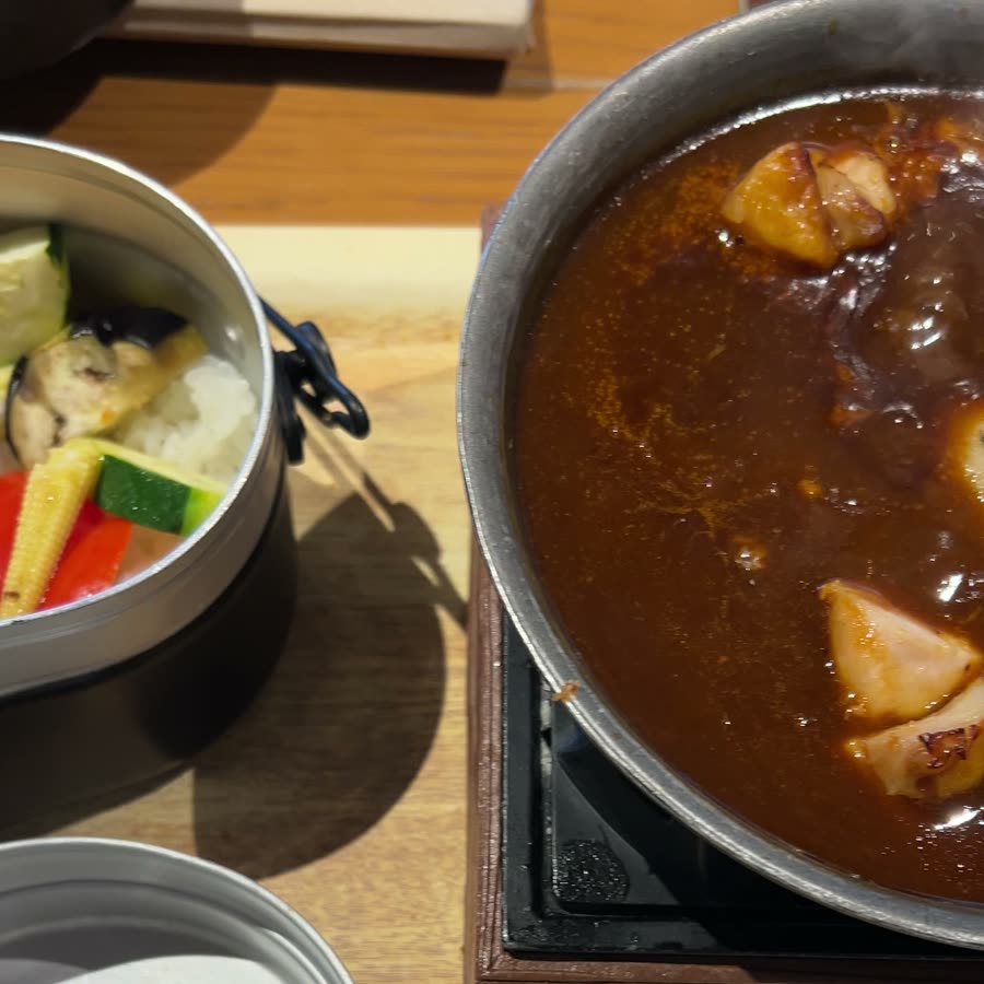 テーブルのコンロにかけられたカレーの鍋と、飯盒に入った野菜