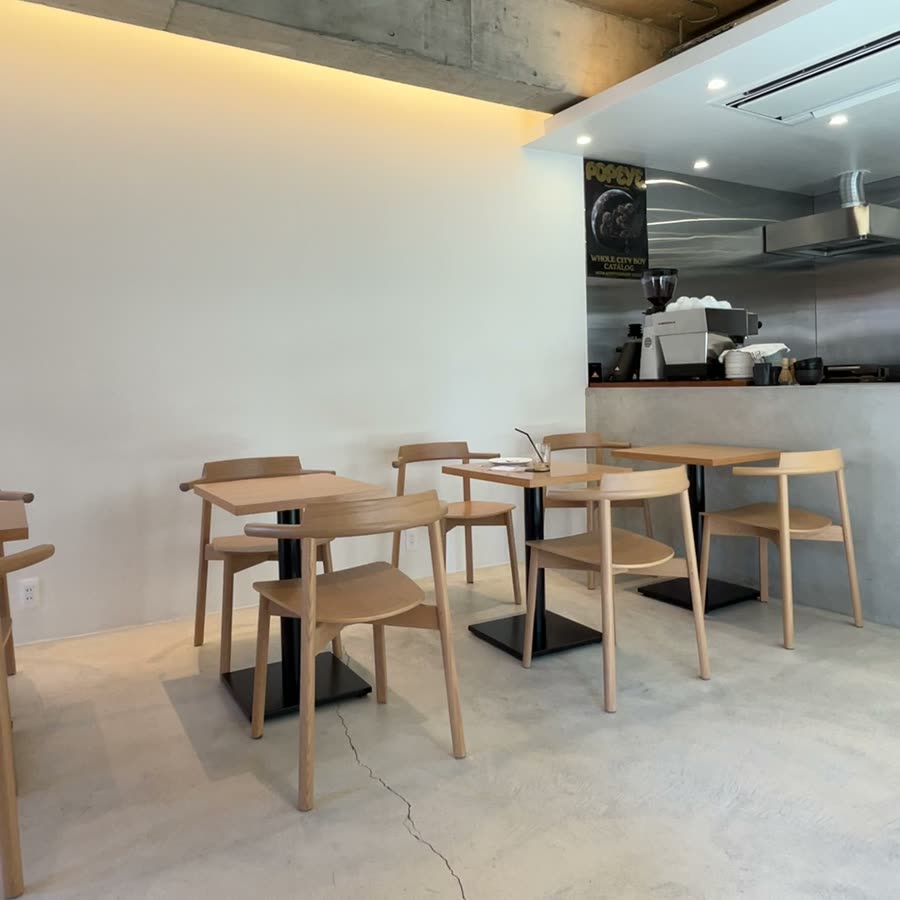 木のテーブルと椅子がならぶ明るい店内